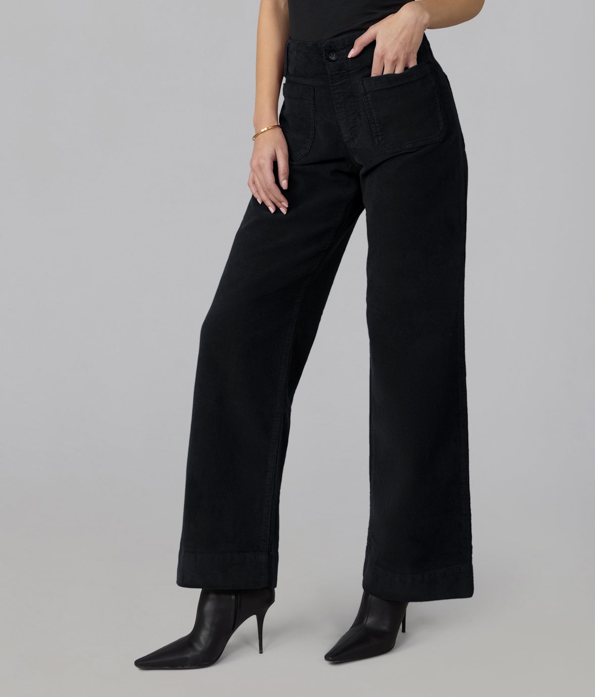 Model wearing Lola Denim COLETTE high-rise wide-leg corduroy jeans in black with patch front pockets and pointed black ankle boots