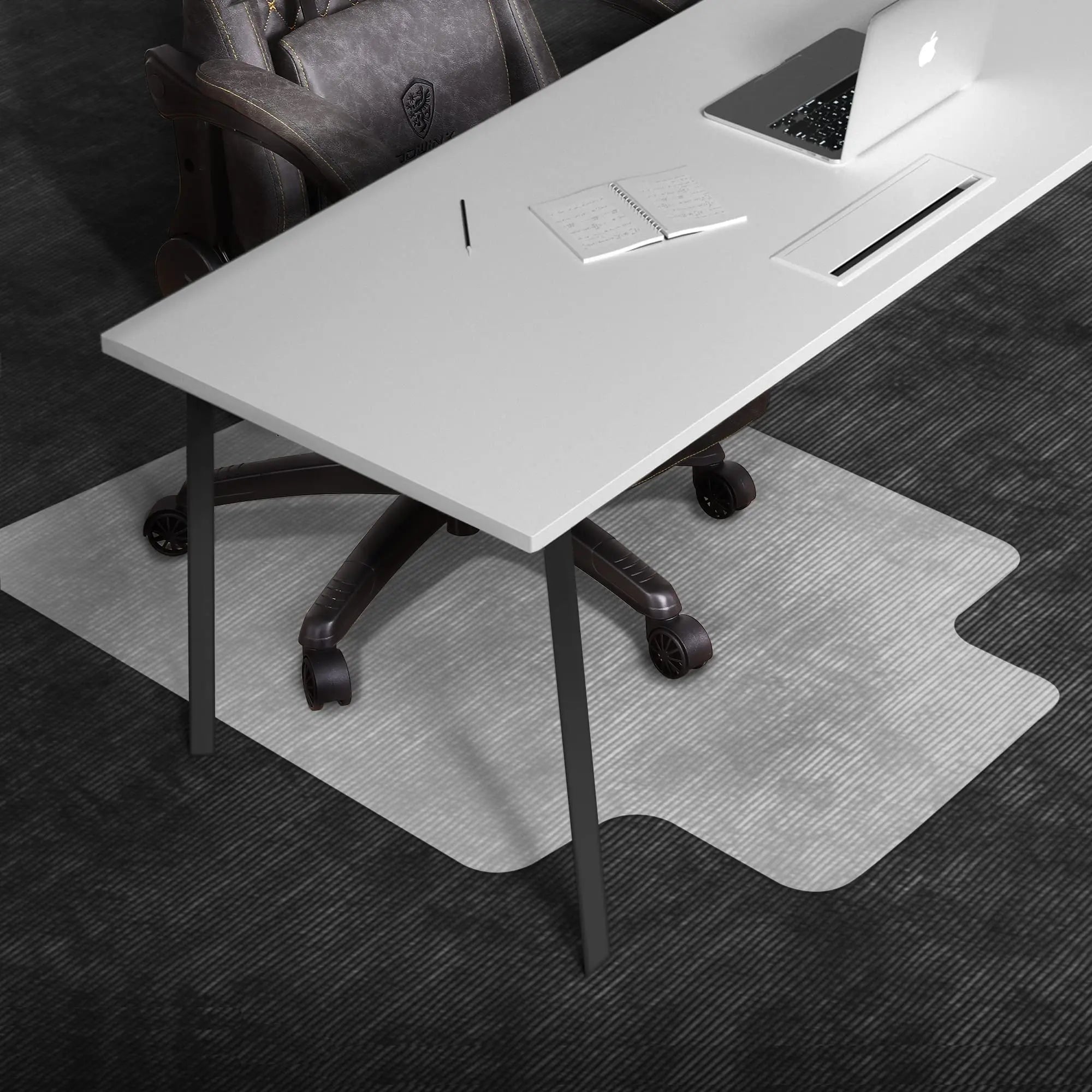 Gaming desk with white surface and black legs on a light gray protective mat under an office chair