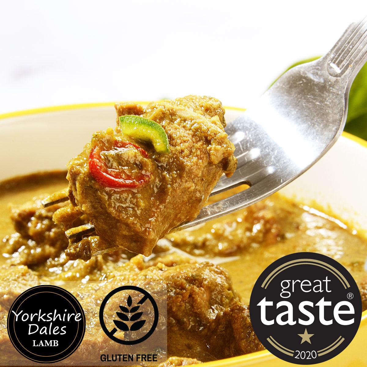 Fork lifting golden lamb curry with green chili and red pepper garnish from yellow-rimmed plate
